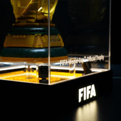 FIFA World Cup Official Trophy on display inside a glass case with yellow lighting and the FIFA logo on the base.