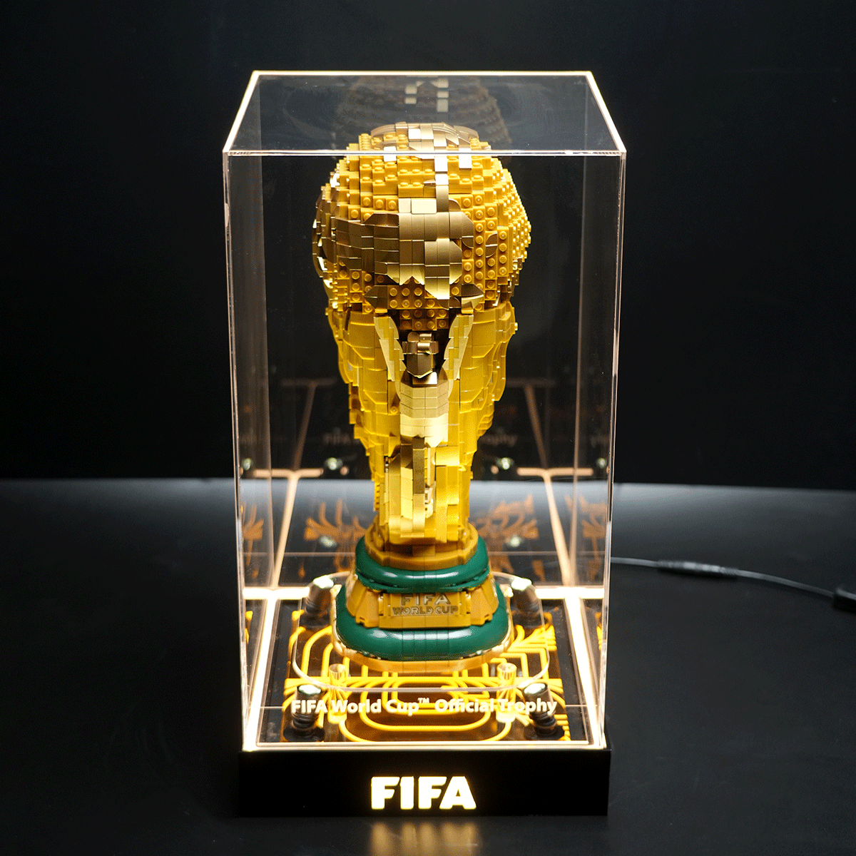 LEGO-crafted FIFA World Cup trophy in a clear display case, mounted on a black base.