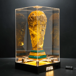 Gold LEGO replica of the FIFA World Cup trophy displayed in a clear glass case on a black pedestal with 'FIFA' lit on the base.