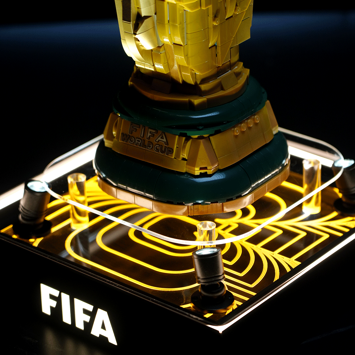 LEGO-style FIFA World Cup trophy replica on a neon-lit display base with 'FIFA' text visible.