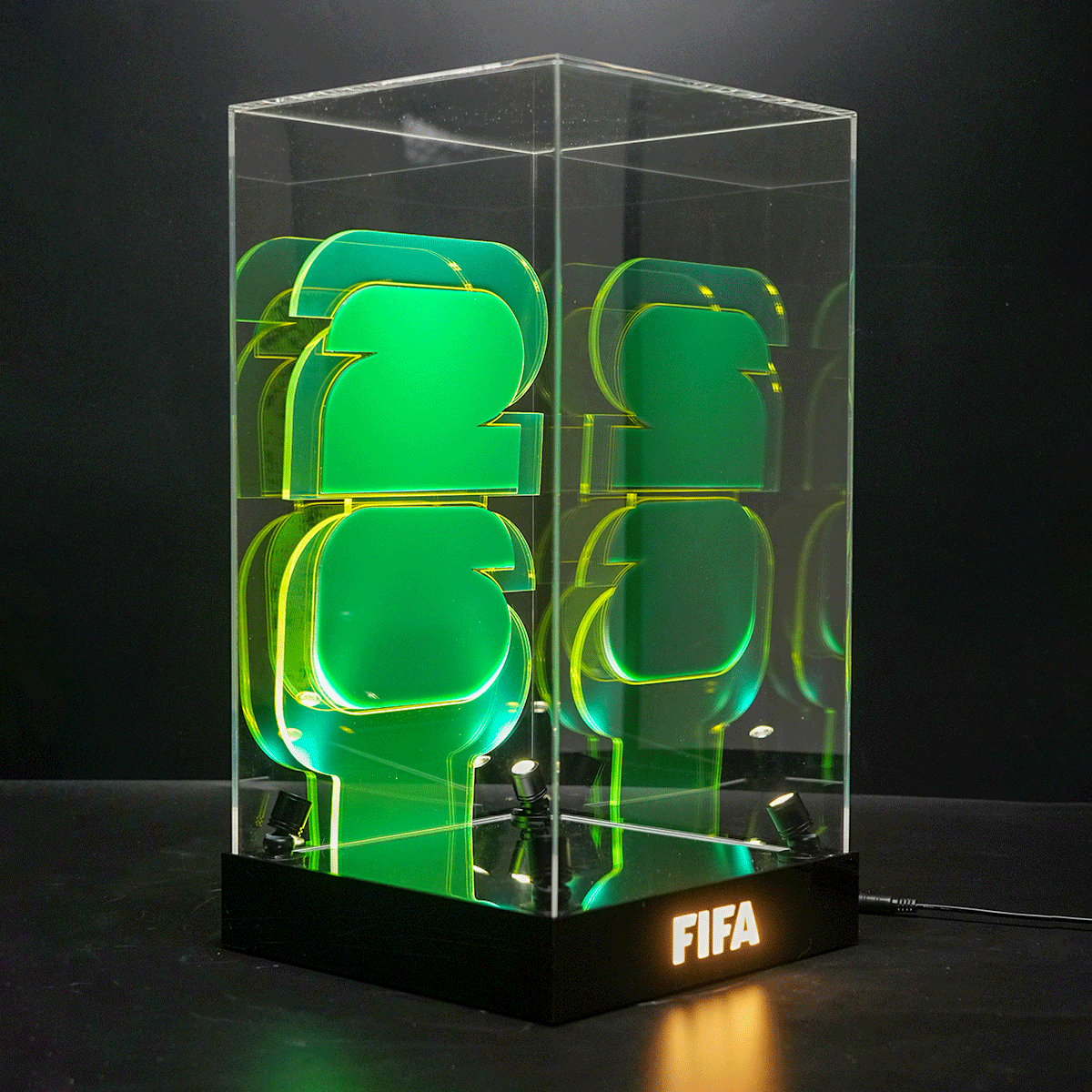 LED desk lamp in a clear acrylic case displaying stacked green 3D shapes, with the FIFA logo lit on the base.