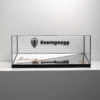 Glass display case with black frame on a white shelf showing a Koenigsegg logo and brand name on the back panel.