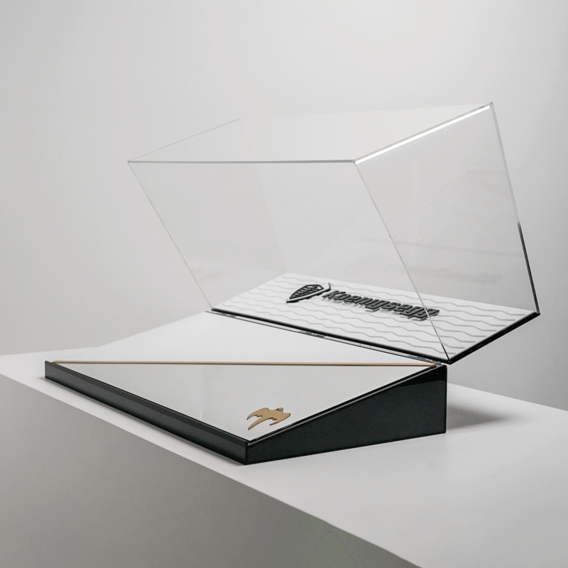Open clear display case atop a black base with gold trim and a small gold emblem, ready to showcase items