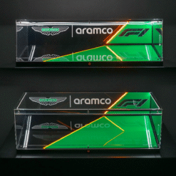 Two clear glass display cases mounted on a dark wall feature Aston Martin and Aramco branding with green and orange neon diagonal accents.