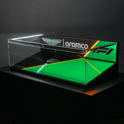 Clear acrylic display case with the Aston Martin Aramco logo and green lighting on a black pedestal.