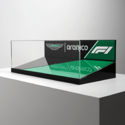 Glass display case with Aston Martin, Aramco and F1 logos on a green mirrored base and black底 pedestal.