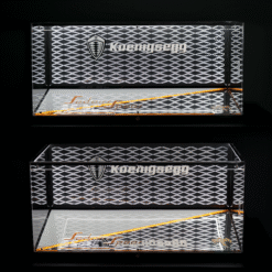 Two reflective display panels with a diamond-patterned grille, Koenigsegg logo and shield, and an orange diagonal accent against a dark background.