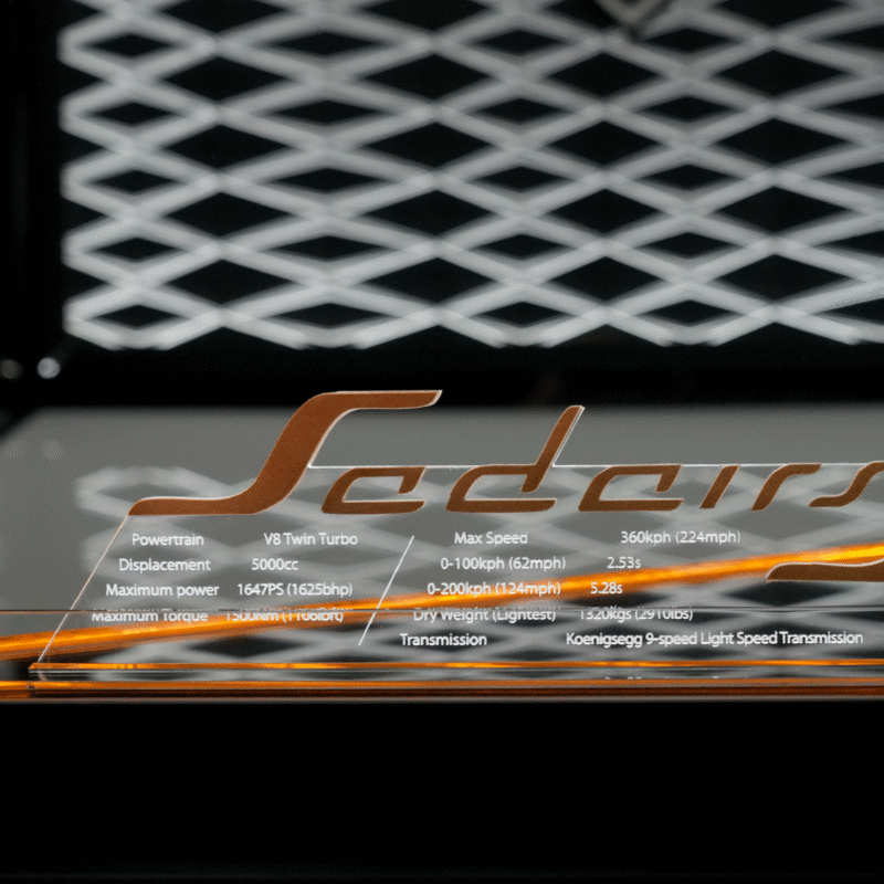 Transparent acrylic car badge reading 'Seders' with specs: V8 twin‑turbo, 5000cc, ~1647PS, max speed ~360 kph (224 mph).