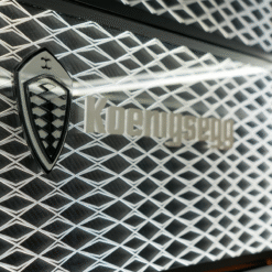Koenigsegg badge on a diamond-patterned car grille, close-up of branding.