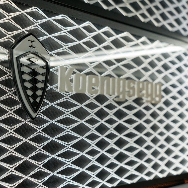 Koenigsegg badge on a diamond-patterned car grille, close-up of branding.