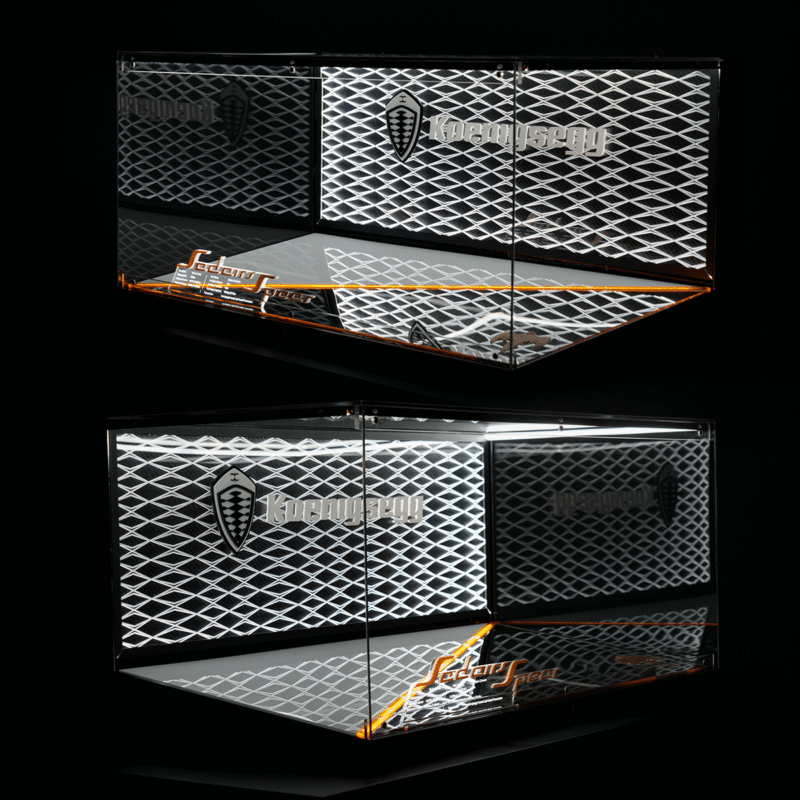 Chrome display cabinet with a diamond-mesh pattern, Koenigsegg branding, and orange edge lighting against a black background.