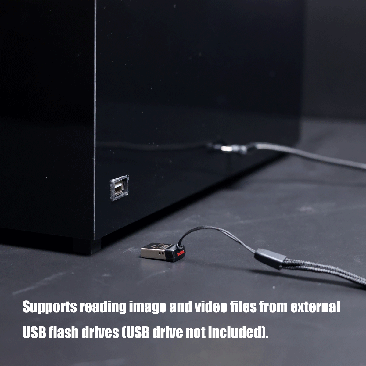 Black device with a USB flash drive plugged in; caption indicates it can read image and video files from external USB drives (drive not included).