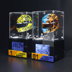 Two race helmets in glass display cases on black pedestals, labeled Lando Norris and Oscar Piastri.