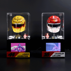 Two glass display cases with yellow and red Ferrari race helmets, each with a small driver figurine and nameplates reading 'Lewis Hamilton 44' and 'Charles Leclerc 16'