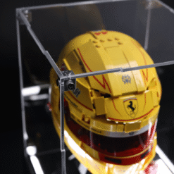 Yellow Ferrari racing helmet encased in a clear display case with metal frame and red visor accents.