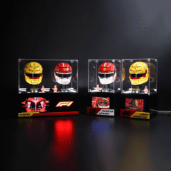 Ferrari Formula 1 helmets on glass display cases against a dark background with driver plaques underneath.