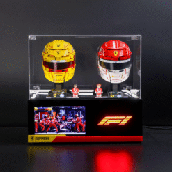 Clear display case with yellow and red Ferrari F1 helmets, three small figurines, and a two-screen setup showing pit crew and the F1 logo on the base.