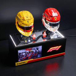 Ferrari F1 display with yellow and red helmets on a glossy black podium, miniature figures, and a screen showing cheering fans.