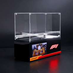 Black display podium with a clear acrylic case on top, illuminated by LEDs, featuring a Formula 1 logo and a team photo of two drivers at the base.