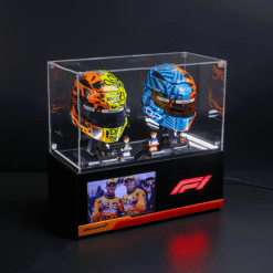 Clear display case with two colorful Formula 1 helmets and two small figurines on a McLaren/F1 pedestal for a product showcase.
